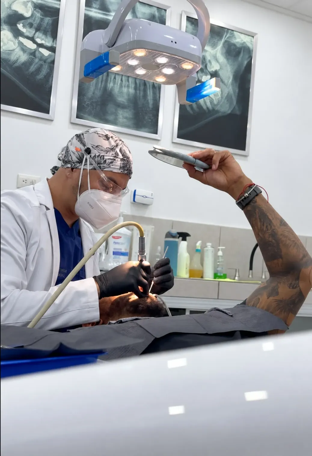 Odontólogo colocando una corona dental en el consultorio, junto a radiografías panorámicas