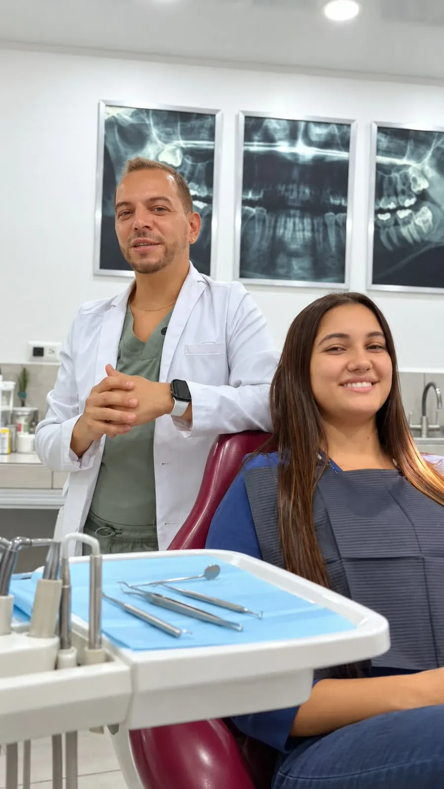 Odontólogo y paciente en el consultorio con radiografías dentales de fondo
