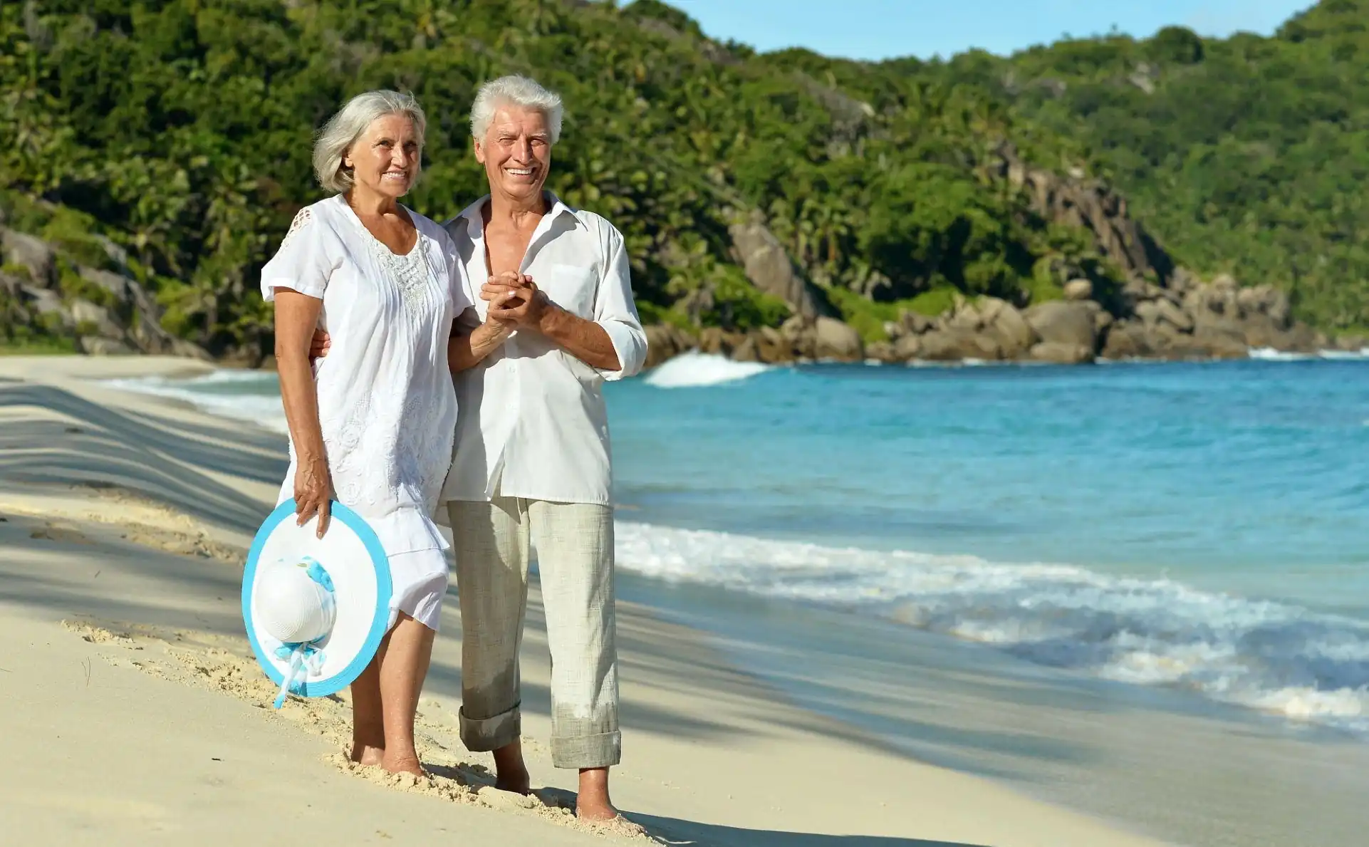 Senior couple smiling on a Costa Rican beach after their dental treatment